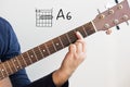 Man playing guitar chords displayed on Whiteboard, Chord A6