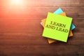 Learn and Lead, the phrase is written on multi-colored stickers, on a brown wooden background. Business concept, strategy, plan, Royalty Free Stock Photo