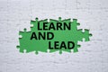 Learn and lead symbol. Concept words Learn and lead on white puzzle. Beautiful green background. Business and Learn and lead Royalty Free Stock Photo