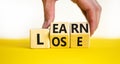 Learn or lose symbol. Concept words Learn and Lose on wooden cubes. Businessman hand. yellow table white background.