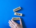 Learn new skills symbol. Concept words Learn new skills on wooden blocks. Beautiful blue background. Businessman hand. Business Royalty Free Stock Photo