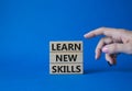 Learn new skills symbol. Concept words Learn new skills on wooden blocks. Beautiful blue background. Businessman hand. Business Royalty Free Stock Photo