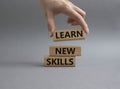 Learn new skills symbol. Concept words Learn new skills on wooden blocks. Beautiful grey background. Businessman hand. Busines