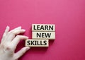 Learn new skills symbol. Concept words Learn new skills on wooden blocks. Beautiful red background. Businessman hand. Business