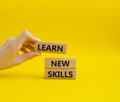 Learn new skills symbol. Concept words Learn new skills on wooden blocks. Beautiful yellow background. Businessman hand.