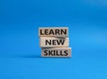 Learn new skills symbol. Concept words Learn new skills on wooden blocks. Beautiful blue background. Business and Learn new Royalty Free Stock Photo