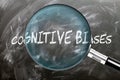 Learn, study and inspect Cognitive Biases. A magnifying glass enlarging word \'cognitive biases\' written on a b