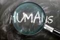 Learn, study and inspect humans - pictured as a magnifying glass enlarging word humans, symbolizes researching, exploring and