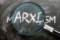 Learn, study and inspect marxism - pictured as a magnifying glass enlarging word marxism, symbolizes researching, exploring and