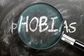 Learn, study and inspect phobias - pictured as a magnifying glass enlarging word phobias, symbolizes researching, exploring and