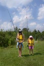 Learn to fish. Two amazing blonde little girl with fishing rod are ready to fish. They are wearing in sunglasses, life jackets.