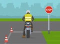 Learner motorcyclist stopped at `Stop` sign. Back view. Junction road priority. Royalty Free Stock Photo