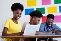 Learning african american female student at computer with group of students