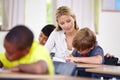 Learning the basics. A young teacher assisting a student with classwork at his desk.