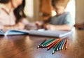 Learning is a family affair. pencils on a table with a mother and son doing homework in the background. Royalty Free Stock Photo