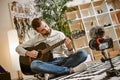 Learning guitar. Bearded male music blogger sitting on the floor at home and recording new guitar lesson for Youtube