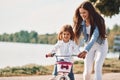 Learning how to drive. Mother with her young daughter is with bicycle outdoors together Royalty Free Stock Photo