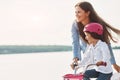 Learning how to drive. Mother with her young daughter is with bicycle outdoors together Royalty Free Stock Photo