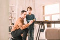 Smart serious adult demonstratin how to use a measuring tape to his son. Royalty Free Stock Photo