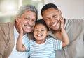 Learning from a king. Portrait of a mature man sitting with his son and holding his grandson at home. Royalty Free Stock Photo