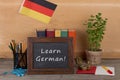 Learning languages concept - blackboard with text "Learn German", flag of the Germany, books, chancellery