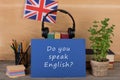 Learning languages concept - blue paper with text "Do you speak English?", flag of the Great Britain, headphones, books Royalty Free Stock Photo