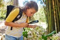 Learning, magnifying glass and girl with flower outdoor for looking at plants at park. Education, child and magnifier Royalty Free Stock Photo