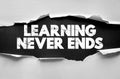 Learning Never Ends message displayed in cracked bold text behind torn paper. Concept for continuous education, knowledge, Royalty Free Stock Photo
