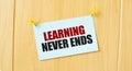 LEARNING NEVER ENDS sign written on sticky note pinned on wooden wall Royalty Free Stock Photo