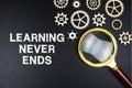 Learning Never Ends text message with magnifying glass on black background Royalty Free Stock Photo