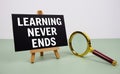 Learning never ends text on paper card with magnifying glass on green background Royalty Free Stock Photo