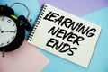 Learning Never Ends text written on notepad with alarm clock flat lay on multicolor pastel background Royalty Free Stock Photo