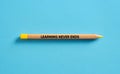 Learning never ends written on a single pencil over blue background Royalty Free Stock Photo