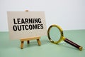 Learning Outcomes text on paper card with magnifying glass on green background Royalty Free Stock Photo