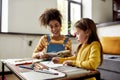 Learning Place. Caucasian little girl spending time with african american baby sitter. Kid is drawing, learning how to Royalty Free Stock Photo