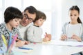 Learning process. Adorable little latin boy drawing something while spending time with his father and siblings at home