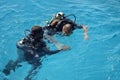 Learning process of scuba diving. Experienced instructor teaches beginner to dive into sea using scuba gear.