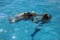 Learning process of scuba diving. Experienced instructor teaches beginner to dive into sea using scuba gear.