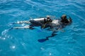 Learning process of scuba diving. Experienced instructor teaches beginner to dive into sea using scuba gear.