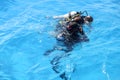 Learning process of scuba diving. Experienced instructor teaches beginner to dive into sea using scuba gear.