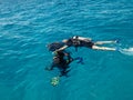 Learning process of scuba diving. Experienced instructors teaches one beginner to dive into sea using scuba gear.