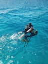 Learning process of scuba diving. Experienced instructors teaches one beginner to dive into sea using scuba gear.