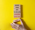 Learning symbol. Wooden blocks with words Design your day to learn something new. Businessman hand. Beautiful yellow background.