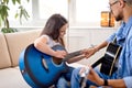 Learning to play the guitar. Nice male teacher explains to child the basics of playing guitar Royalty Free Stock Photo