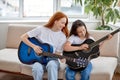 Learning to play the guitar. Redhead Female teacher explains to child how to play guitar Royalty Free Stock Photo