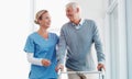 Learning to walk with great support. a senior man using a walker with the assistance of a young nurse. Royalty Free Stock Photo