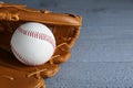 Leather baseball glove with ball on grey wooden table, closeup. Space for text Royalty Free Stock Photo