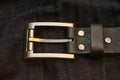 Leather belt with simple rectangular iron buckle on dark blue denim jeans