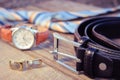 Leather belt, tie, cufflinks and watches on the old wood background.