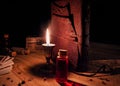 Leather bound tome, a candle and a potion on a wooden surface